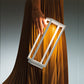 A person holds the Zafferano Home Pro Lamp in white, a rectangular minimalist rechargeable lamp, against pleated brown fabric.