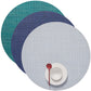 Three Mini Basketweave Round Placemats in teal, blue, and light gray are stacked for a vibrant dining look. On the light gray mat, a white cup and saucer with a red spoon are arranged elegantly.
