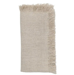A Kim Seybert Fringe Napkin from the set of 4, in beige and adorned with delicate silver lurex threads, neatly folded.