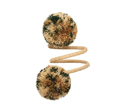 The Kim Seybert Casbah Napkin Ring features a coiled rope design with large tan and green pom-poms at each end, inspired by organic elegance, displayed on a white background.
