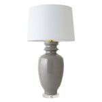 The Marathon Table Lamp in Fossil Grey features a glossy hand-thrown ceramic base with a custom glaze, gold neck accents, a clear round base, and is topped with a white fabric shade.