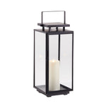 The Napa Alden Outdoor Lantern Small is a black metal and glass lantern with a handle, showcasing a glowing white pillar candle inside—ideal for stylish outdoor lighting.