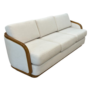 The Schooner Sofa in Outdoor Ivory Chenille is a three-seat sofa with wooden trim, plush seat and back cushions, and armrests—ideal for coastal living and adding luxury to your home.
