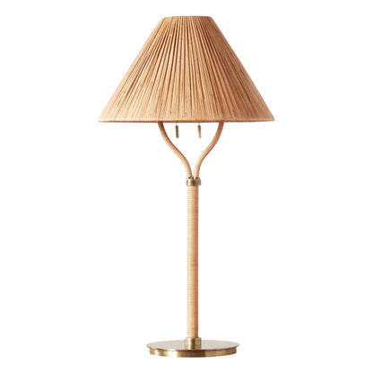The Delphine Table Lamp features a brass base, slender stem, and a handcrafted rattan lampshade—ideal for bringing Parisian apartment charm to any space.