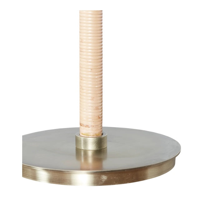 A close-up of the Delphine Table Lamp, featuring a beige ribbed cylindrical rattan shade on a round metallic base, evoking chic Parisian apartment style.