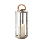 The Dockside Lantern features a metal and glass design with a natural teak handle, housing a white pillar candle for a blend of rustic charm and elegant style.
