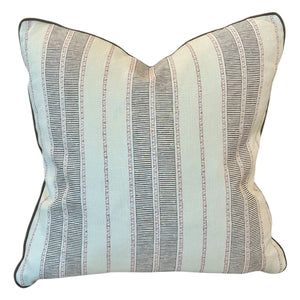 The Sifnos Peat Pillow features a cream base with thin vertical black and brown stripes, accented by dark piping on the edges for a modern look that showcases exceptional craftsmanship.