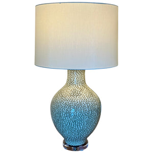 The Athens Large Green Dappled Lamp features a round, textured ceramic base with a spotted pattern and a large cream-colored cylindrical shade—an artistic statement for bespoke lighting.