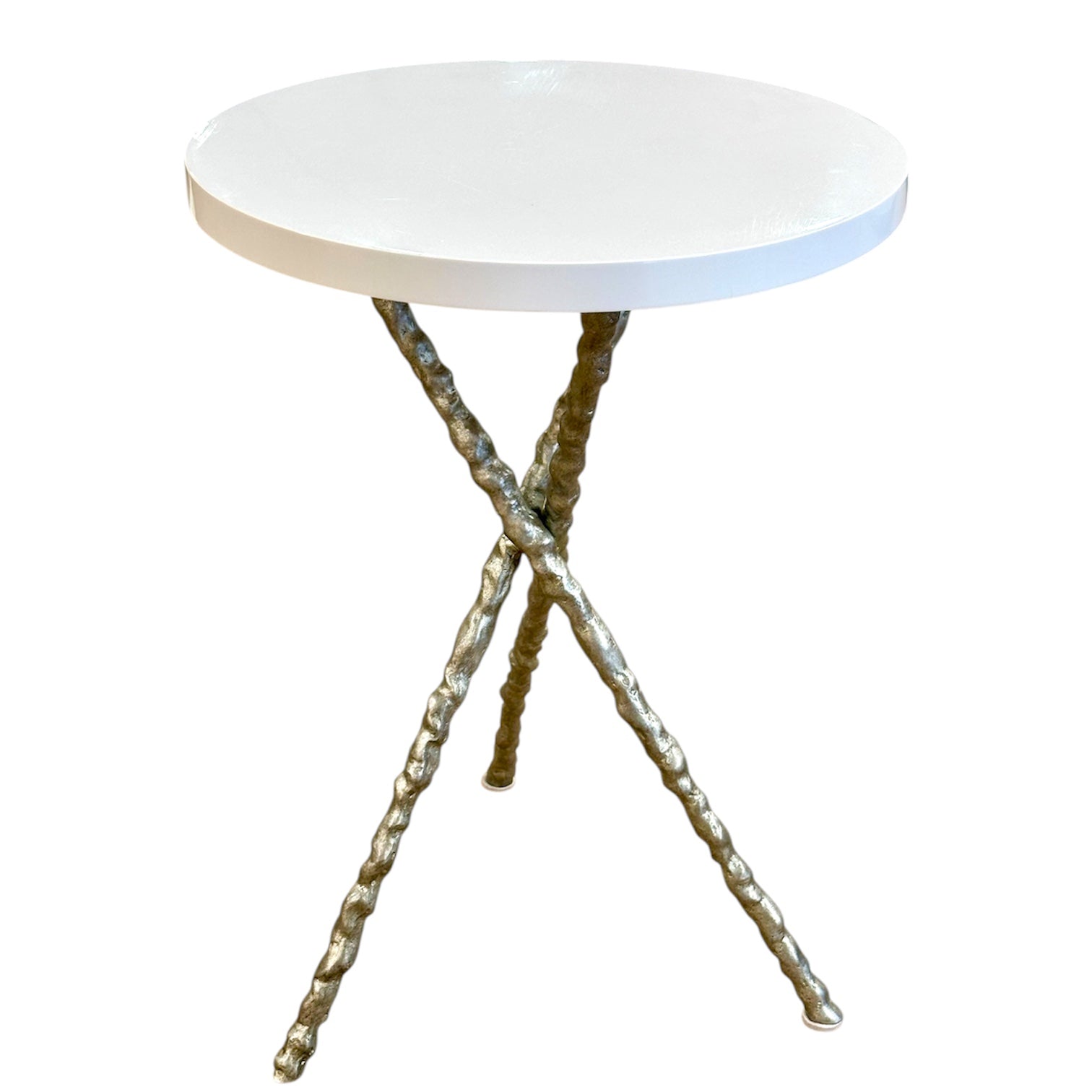 The Diego Side Table features a small round white resin top supported by three twisted iron legs in an intersecting minimalist design.