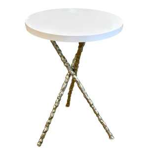 The Diego Side Table features a small round white resin top supported by three twisted iron legs in an intersecting minimalist design.