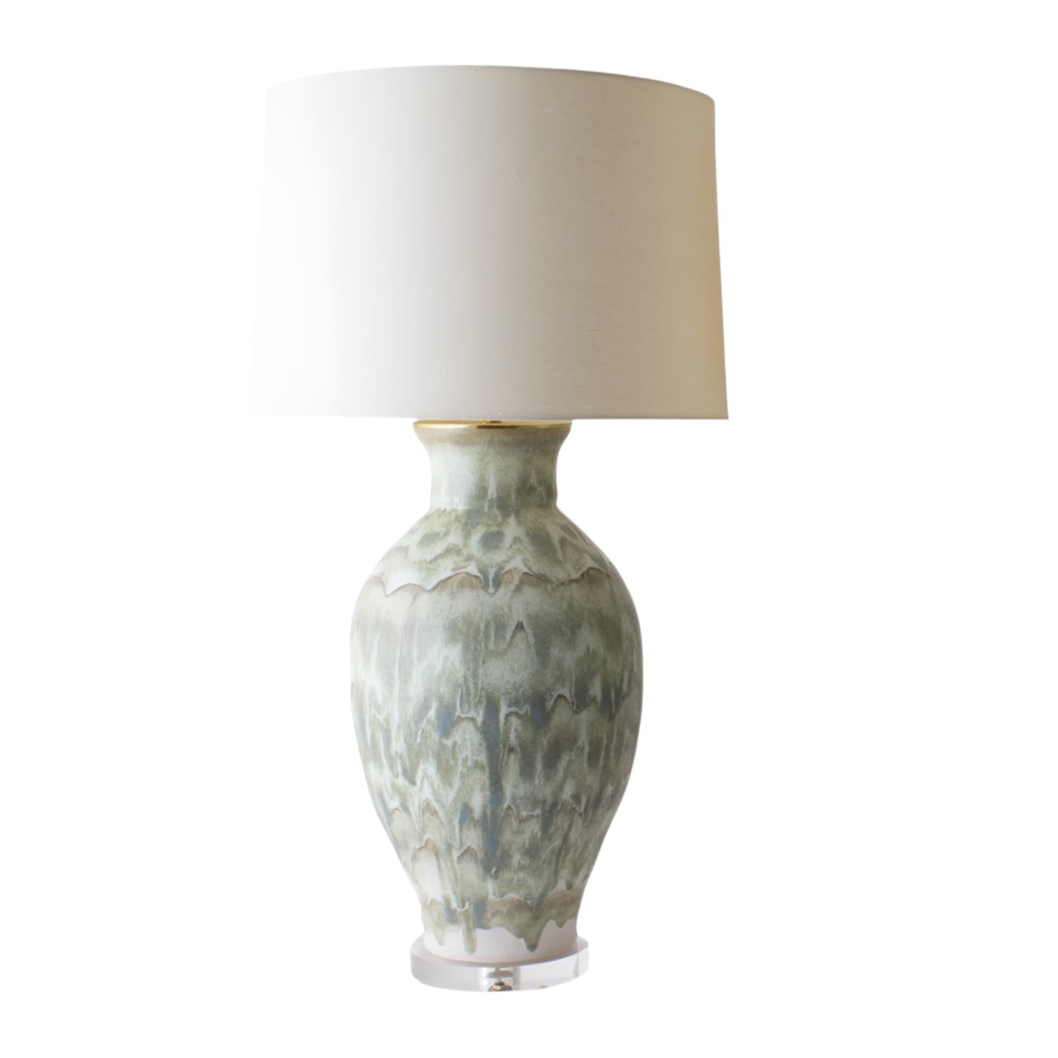 The Matagorda Lamp in Green Drip and Brass Base features a patterned light green ceramic base and a large white drum shade, highlighting artistic excellence in ceramics, shown on a white background.