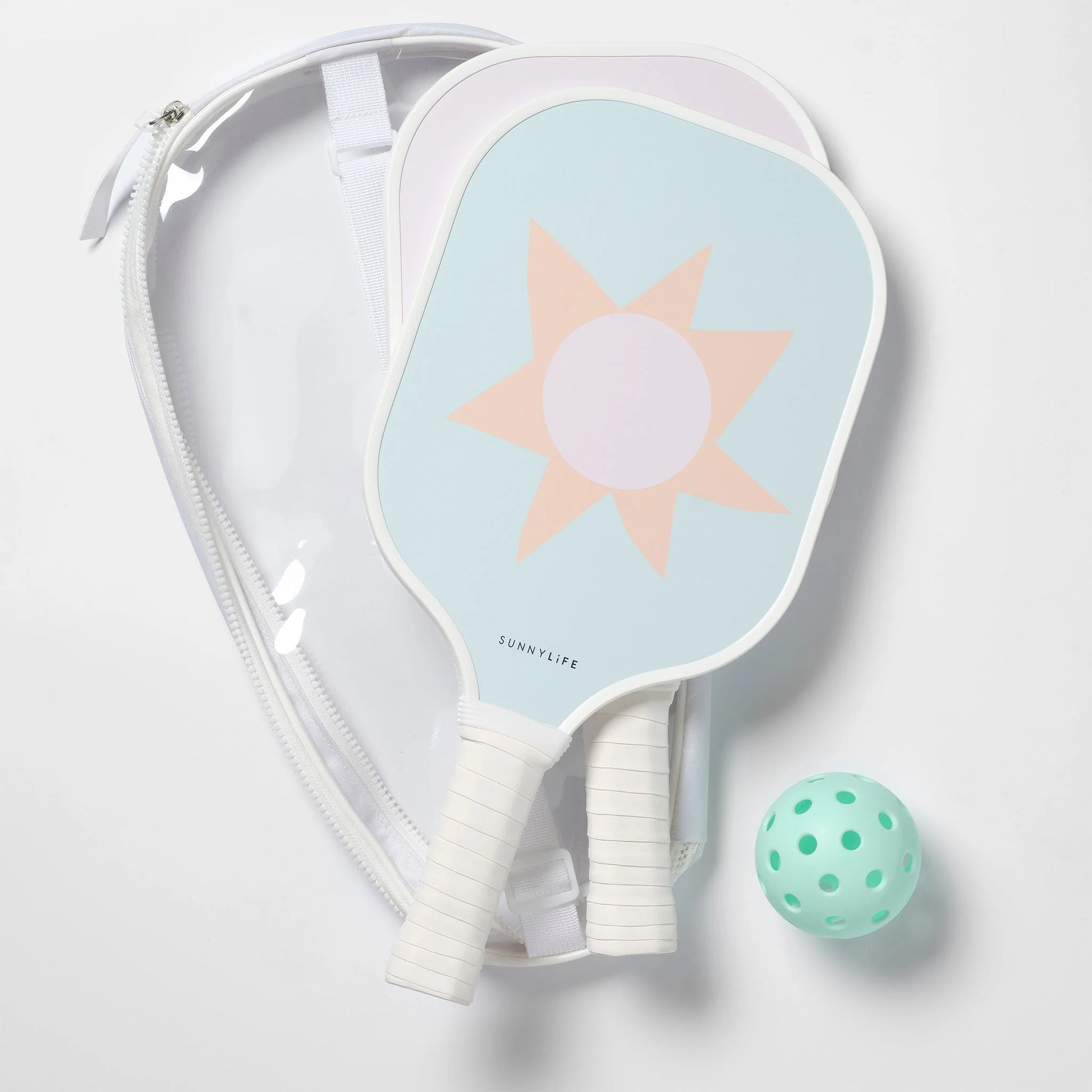 The SUNNYLiFE Pickleball Set in Rio Sun Multi features two sun-patterned paddles with a Polymer Honeycomb core, a light green perforated ball, and a clear carrying case, all shown on a white surface.