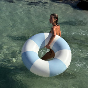 A woman stands in shallow water, holding the SUNNYLiFE Poolside Tube Float in Duck Egg Blue, from Australia’s authentic summer style brand.