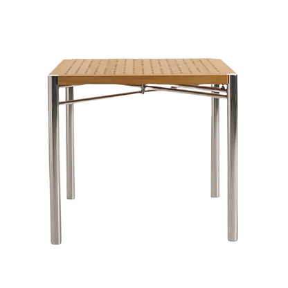 The Sundeck Folding Table is a square teak dining table with a perforated wooden top and four cylindrical marine-grade stainless steel legs, displayed against a plain white background.