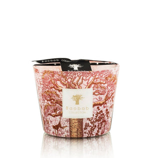 A decorative Baobab Collection Sacred Trees Woroba Candle with a pink tree design, featuring a white label with a gold baobab tree logo and text. Infused with hints of sandalwood, it has a black ribbon attached to the top.