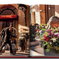 A woman carries a large bouquet of flowers outside Plaza Athenee, while two hotel staff members showcase French hospitality by moving luggage in the background.