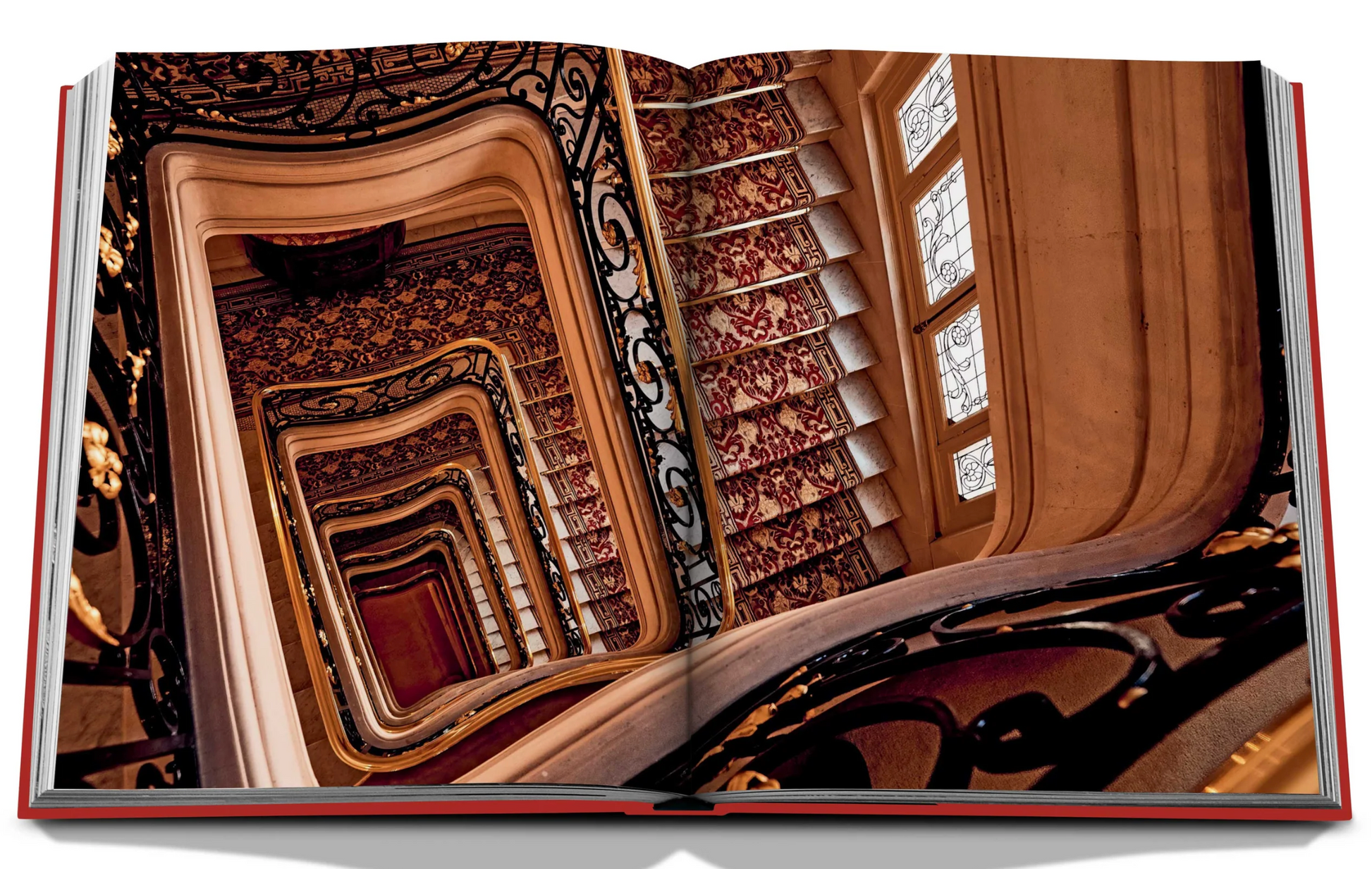 Open book showcasing a photograph of a spiral staircase with ornate railings and patterned walls, viewed from above, reminiscent of the elegance found at Plaza Athenee and the charm of French hospitality.