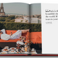 An open book shows a man in a robe lounging on a patio at Plaza Athenee with a view of the Eiffel Tower, surrounded by a spread of food and drinks prepared by Jean Imbert. Text reads, "Paris is the most beautiful city in the world. -Lou Radziwill.