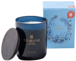 A dark blue candle jar with a black lid labeled "Thucassi Ocean Candle Collection, Coral Garden" is beside its light blue box featuring marine illustrations, reminiscent of an effervescent wine’s freshness.