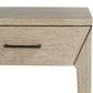 Close-up of the Dublin Desk, a compact piece with a light wood finish and a single drawer accented by a sleek metal handle. Only part of the desk’s front and one leg are shown.
