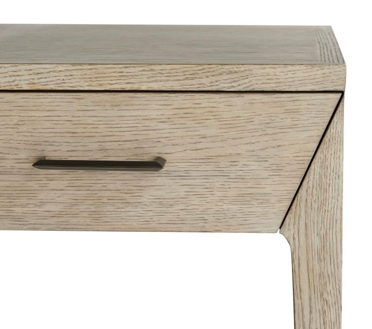 Close-up of the Dublin Desk, a compact piece with a light wood finish and a single drawer accented by a sleek metal handle. Only part of the desk’s front and one leg are shown.