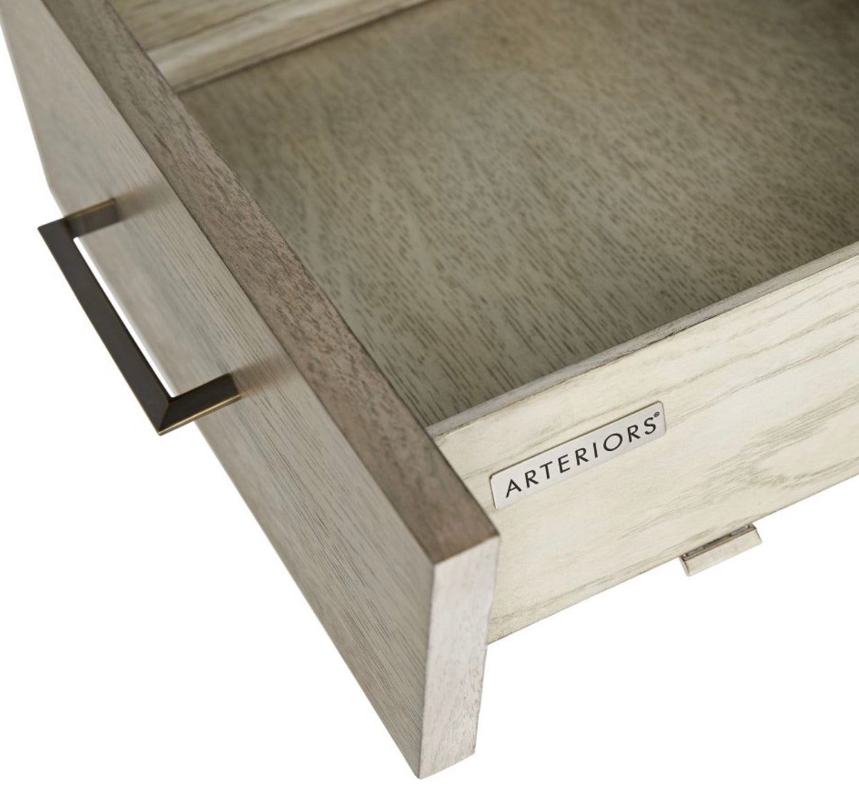 A close-up of an open solid oak drawer with a metal handle on the Dublin Desk, featuring a label inside that reads "Arteriors.