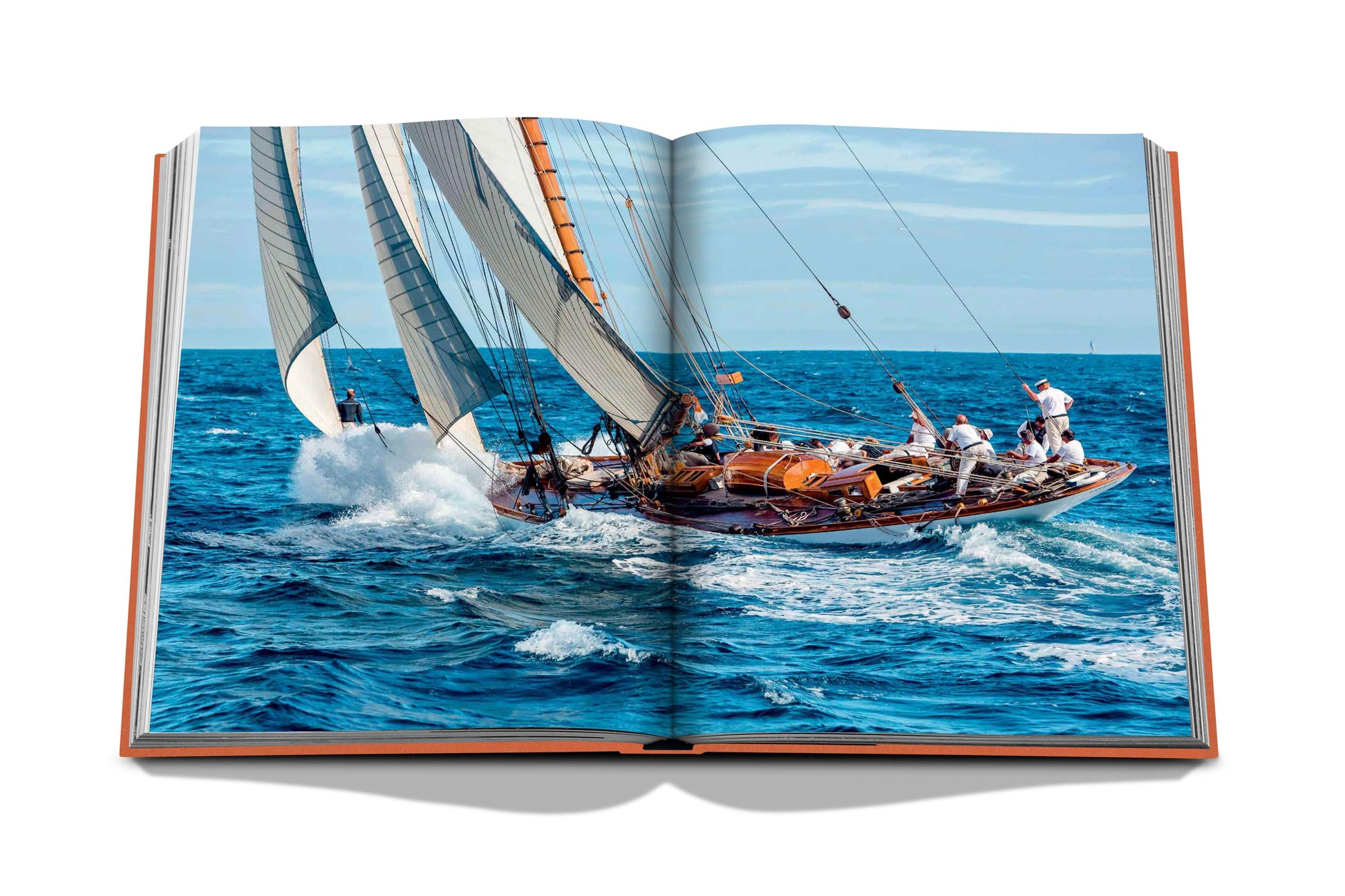 Open book displaying an image of a sailboat with multiple people on board, navigating through blue ocean waters on a sunny day at St Tropez Soleil.