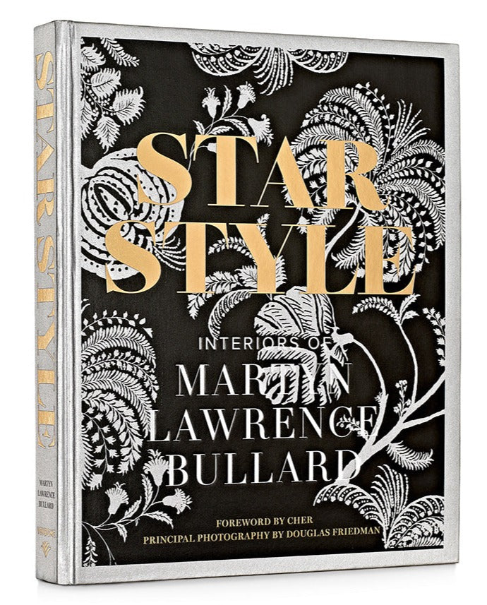 Book cover of "Star Style: Interiors of Martyn Lawrence Bullard" by Martyn Lawrence Bullard, featuring black and white floral designs and gold text. Foreword by Cher, principal photography by Douglas Friedman, showcasing eclectic interiors of celebrity homes.