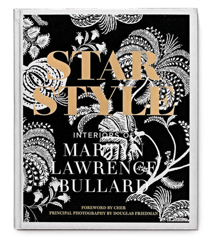 Book cover titled "Star Style: Interiors of Martyn Lawrence Bullard" by Martyn Lawrence Bullard with a foreword by Cher and photography by Douglas Friedman. The cover features a black and white floral pattern, gold text, and showcases eclectic interiors from celebrity homes.