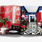 An open book displaying an interior design spread featuring a red bathroom with zebra wallpaper on the left and a hallway with black-and-white checkered floor tiles and blue walls on the right, showcasing The Big Book of Chic's eclectic design style.