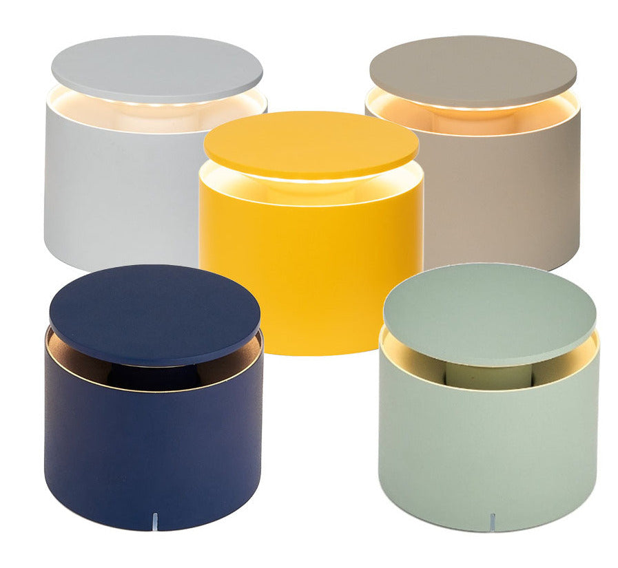Five Zafferano PushUp Pro cordless table lamps in gray, yellow, navy blue, and light green are displayed in a semi-circle with illuminated tops, showcasing the collection’s versatile and modern design.