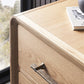 Close-up of the Form Dresser in light wood with spacious drawers and organic bronze pulls, topped with a book and decorative object, positioned near a window overlooking trees.