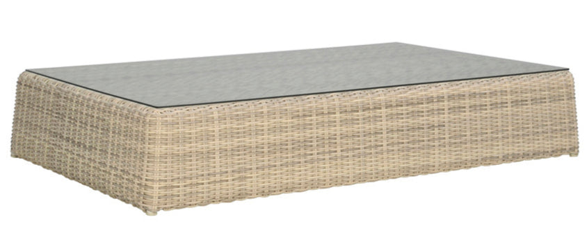 The Zeya Grande Outdoor Coffee Table features a rectangular wicker design with a glass top, weather-resistant light beige weave, and a low-profile look for refined outdoor style.