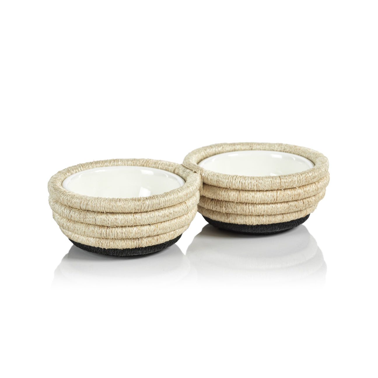 The Zodax Martigues Abaca Bowl Collection features two round ceramic bowls with textured, rope-like exteriors and dark bases, showcasing native craftsmanship as they sit side by side on a reflective white surface.