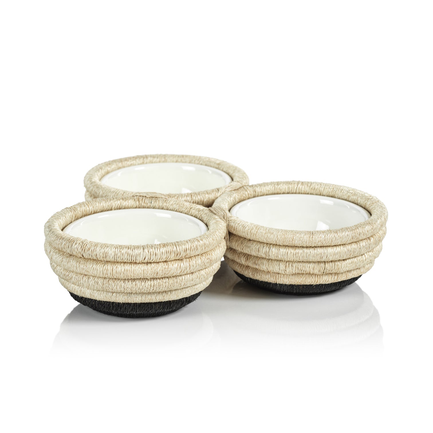 The Zodax Martigues Abaca Bowl Collection, featuring three ceramic bowls with woven rope textures that highlight native craftsmanship, are elegantly displayed on a reflective surface.