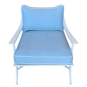 The Haret Outdoor Lounge Chair features blue cushions with white piping, a matching backrest, and metal armrests and legs—a stylish, comfortable addition to any metal outdoor furniture collection.