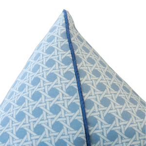 Close-up of a 22" x 22" Cane Mineral Pillow corner, featuring a geometric white lattice pattern and blue piping, filled with 100% down and set against a white background.