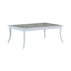 The Bermuda Coffee Table features a light gray rectangular frame, gently curved legs, and a cement-look tabletop with a porcelain inlay—ideal for outdoor use.