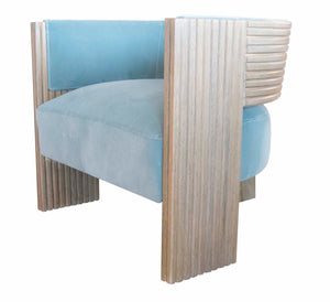 Light blue Kanan Lounge Chair with wooden side panels featuring vertical grooves evokes a touch of Marmol Radziner sophistication. The chair has a modern, boxy design with a cushioned seat and back, seamlessly blending contemporary aesthetics with classic charm.