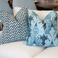Two Breach Candy Blue Pillows, featuring a blue and white pattern and crafted from premium materials, are placed on a white upholstered sofa.