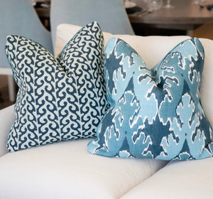 Two Breach Candy Blue Pillows, featuring a blue and white pattern and crafted from premium materials, are placed on a white upholstered sofa.