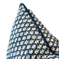 A close-up of the Burma Indigo Outdoor Pillow, featuring a navy blue and white pattern, textured fabric, and dark blue piped edge, set against a white background.