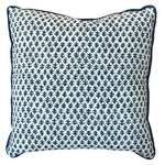 The Burma White Indigo Outdoor Pillow features a white background with a dark blue leaf-like pattern and dark blue edge piping, crafted from premium materials to elevate any space.