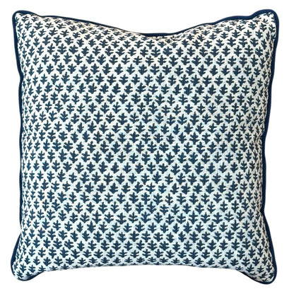 The Burma White Indigo Outdoor Pillow features a white background with a dark blue leaf-like pattern and dark blue edge piping, crafted from premium materials to elevate any space.