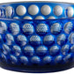 The Mario Luca Giusti Lente Acrylic Collection features a blue bowl with a raised circular pattern that adds a touch of elegance, perfect for outdoor entertaining and designed to brighten any table setting.