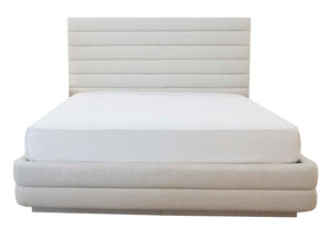 A neatly made custom bed with a white padded headboard featuring channeled detailing and matching white bedding. The Channel Bed, King has horizontal lines.