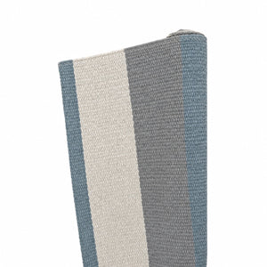 A close-up of the Lina Rug in Chalk, Dark Grey & James Blue shows its hand-woven texture with vertical stripes in blue, gray, and off-white on a white background.
