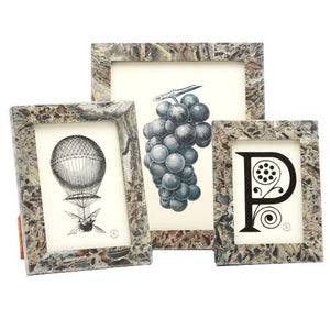 The Corsica Frame Collection features three decorative frames with a marble pattern, showcasing black and white illustrations of a hot air balloon, grapes, and the letter "P" with floral accents.