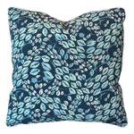 The Cowrie Shell Navy Outdoor Pillow features a dark blue background with a leafy pattern in light blue, green, and white, crafted from premium materials for lasting comfort.
