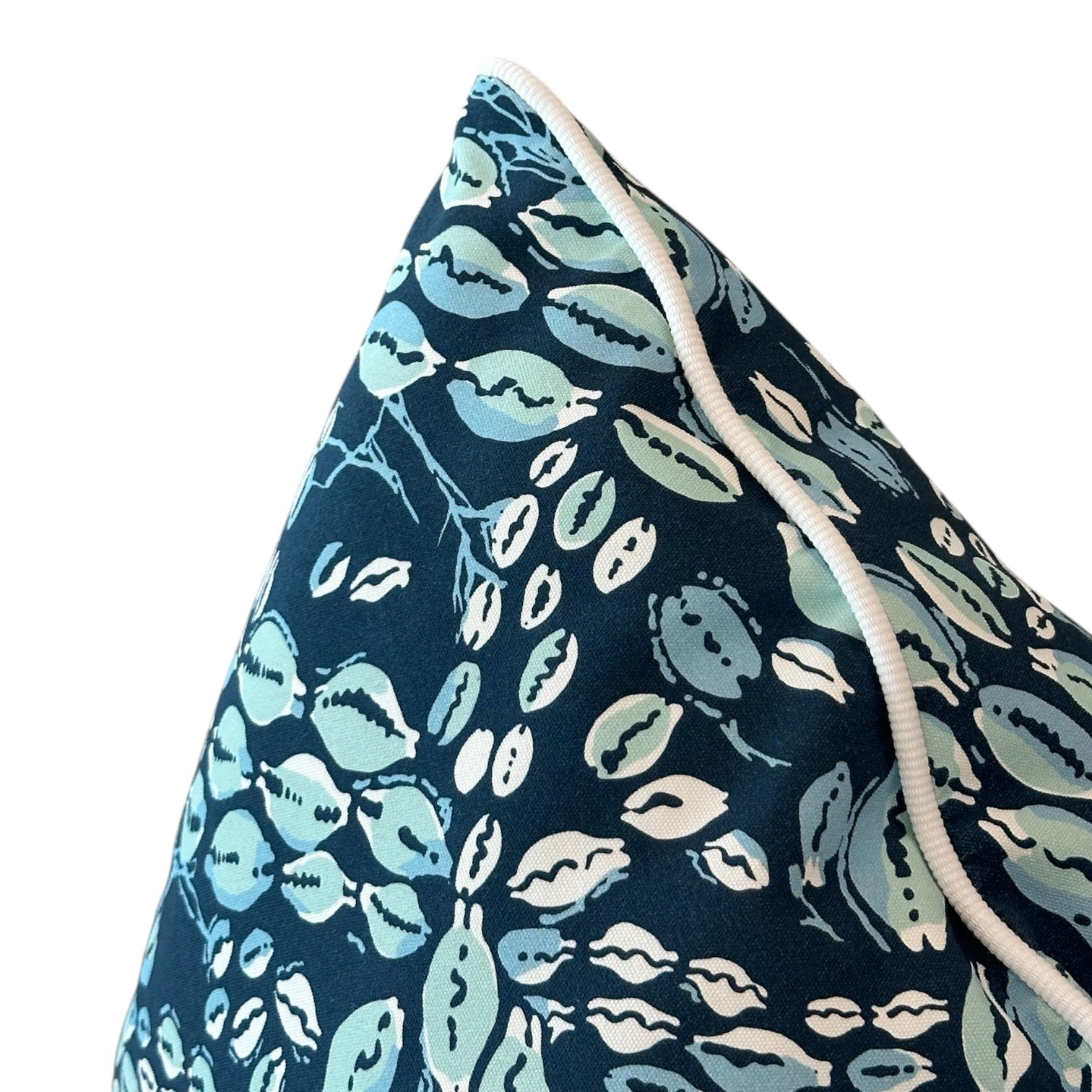 Close-up of the Cowrie Shell Navy Outdoor Pillow, custom-made with a blue and white botanical pattern and white piped edging, crafted from premium materials against a white background.